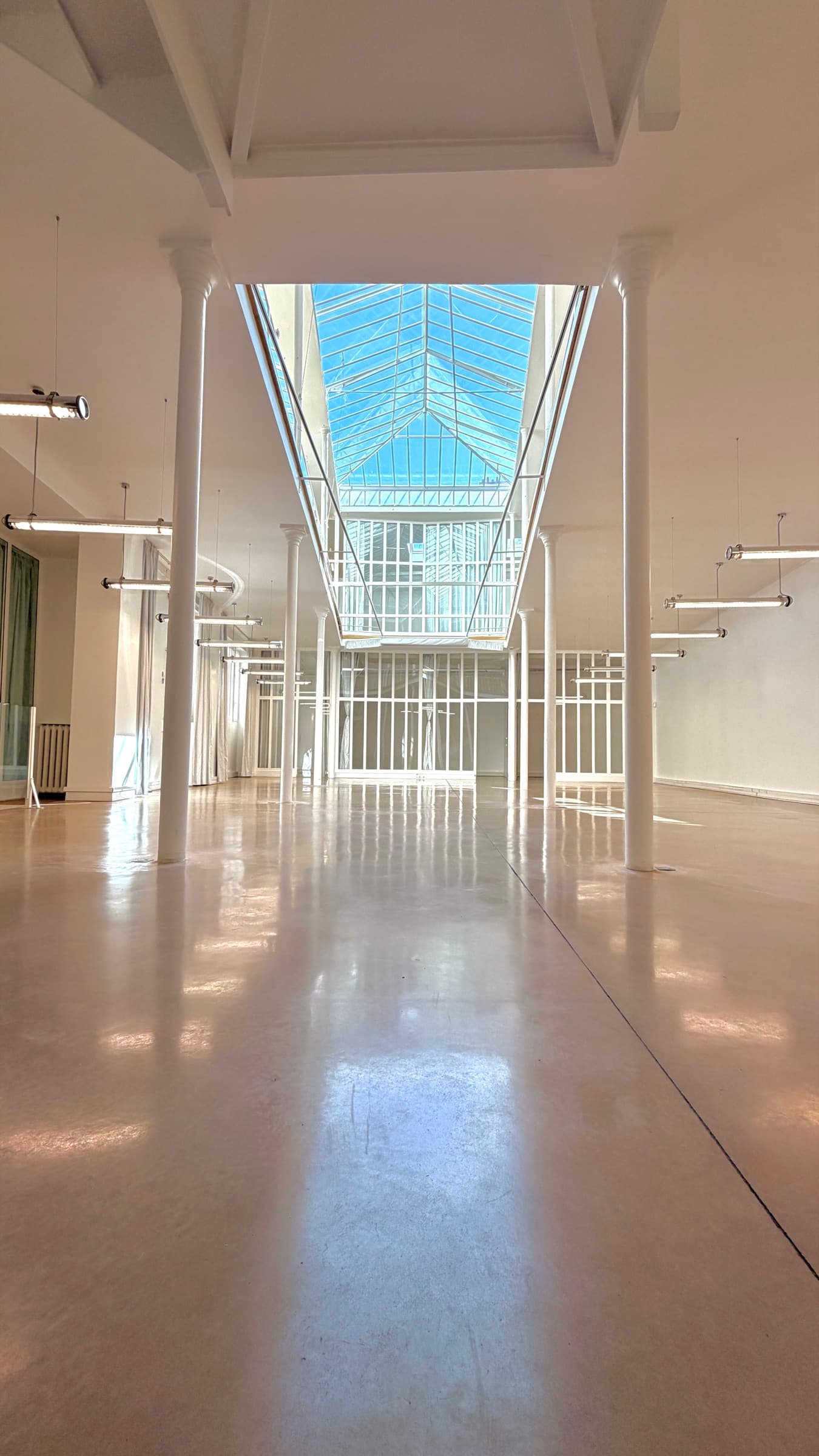 Axe central du plateau RDC vers la verrière zénithale, colonnes symétriques — lieu événementiel Paris