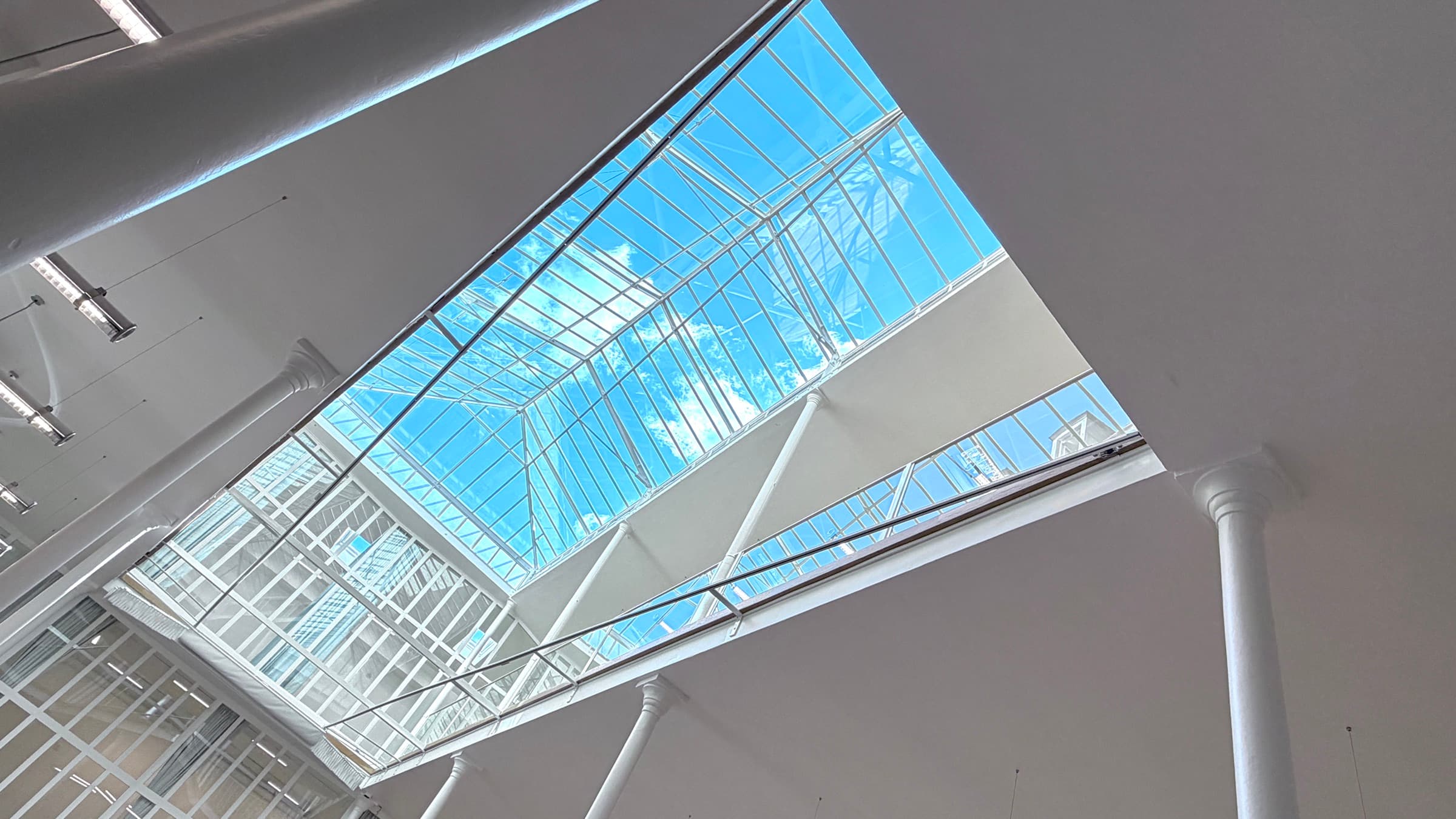 Contre-plongée graphique sur la verrière zénithale et le ciel bleu — Loft République